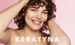 Uśmiechnięta kobieta z kręconymi włosami. Napis "KERATYNA" sugeruje, że to zabieg na włosy, który sprawia, że są zdrowe i lśniące.