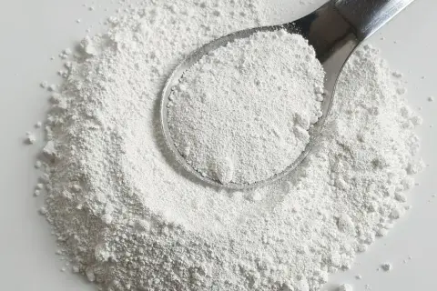 Biały proszek na łyżce i rozsypany na powierzchni. Czy to potencjalna **titanium dioxide szkodliwość**?
