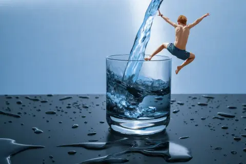 Chłopiec skacze do szklanki z wodą, jakby odkrywał, czym jest hydroterapia.