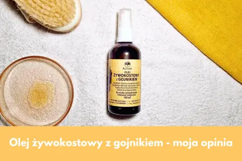 Olej żywokostowy z gojnikiem w buteleczce z atomizerem, obok kieliszka z płynem i szczotki do masażu. Naturalna pielęgnacja.