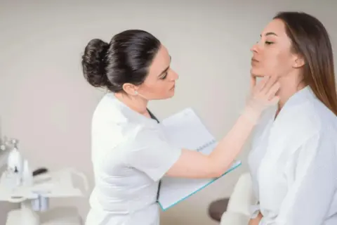Dermatolog bada skórę pacjentki, by ocenić jej stan i dobrać odpowiednie zabiegi.